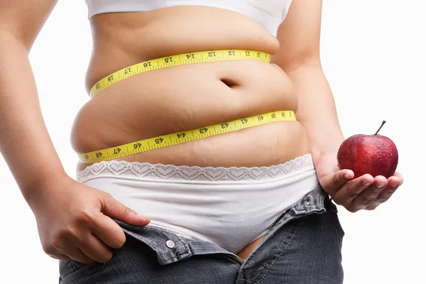 Mulher gorda com jeans descompactados segurando maçã — Fotografia de Stock