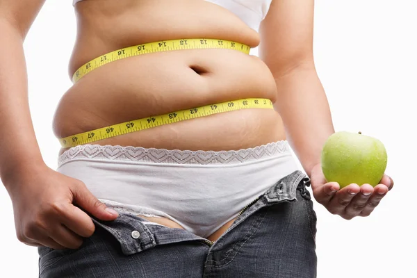 Fat woman with unzip jeans holding apple — Stock Photo, Image