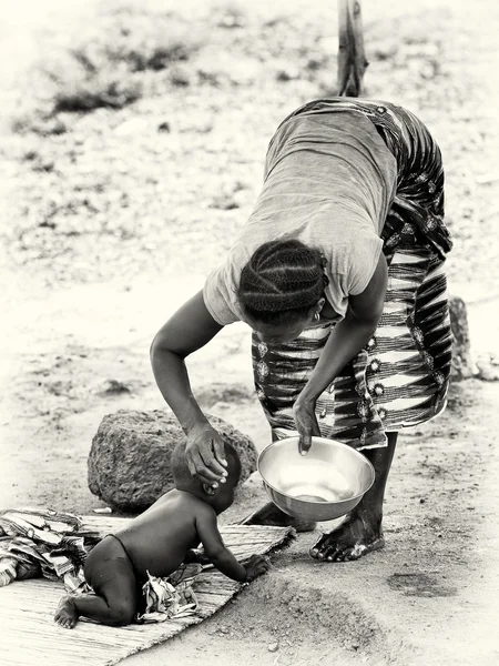 stock image Benin woman gives her baby to drink from a dish