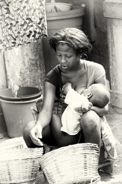 Gana'lı kadın bebeğini bir meme ile beslenir.